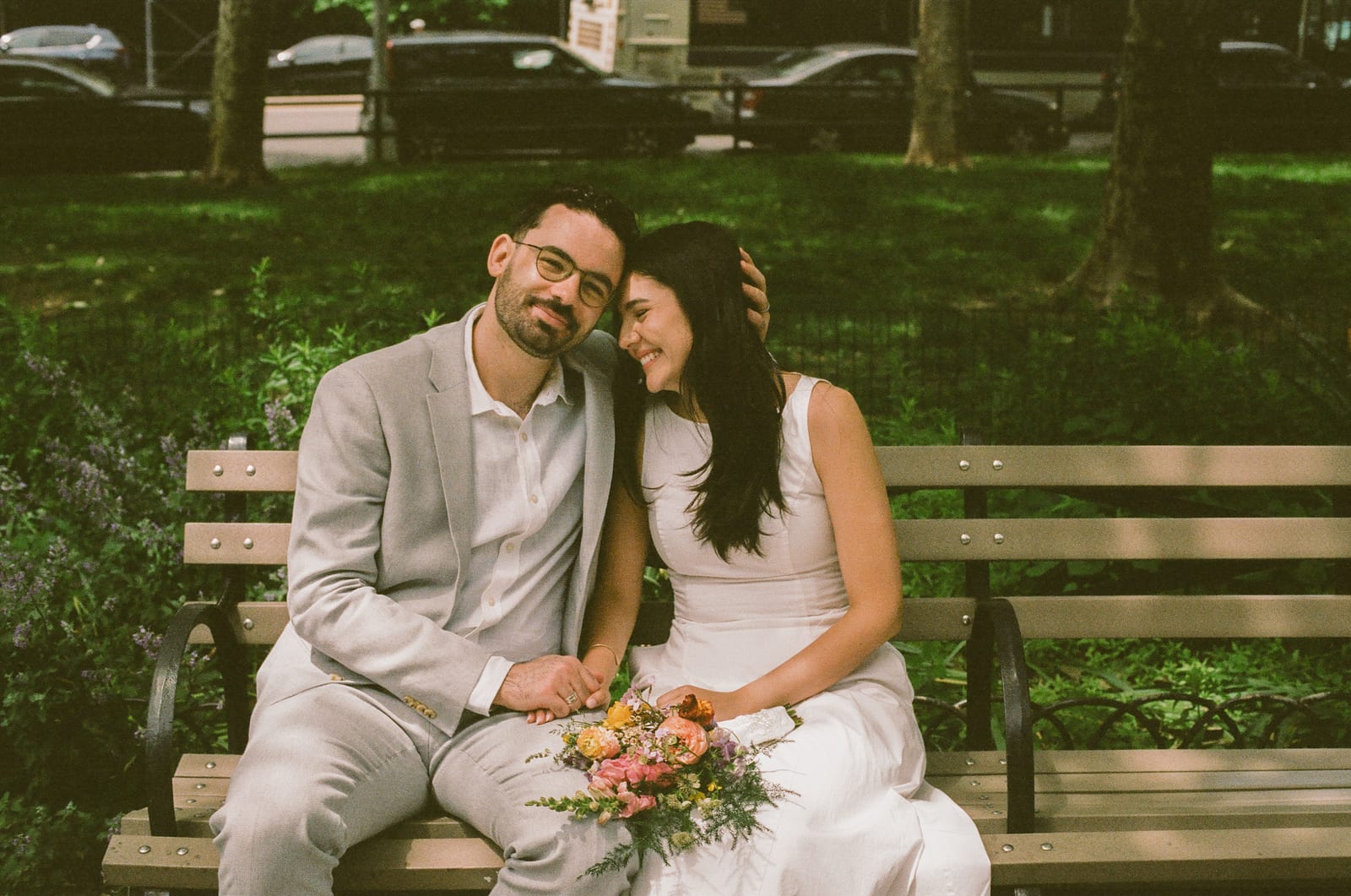 Katherine and Liam on a park bench in Brooklyn with the wedding bouquet
