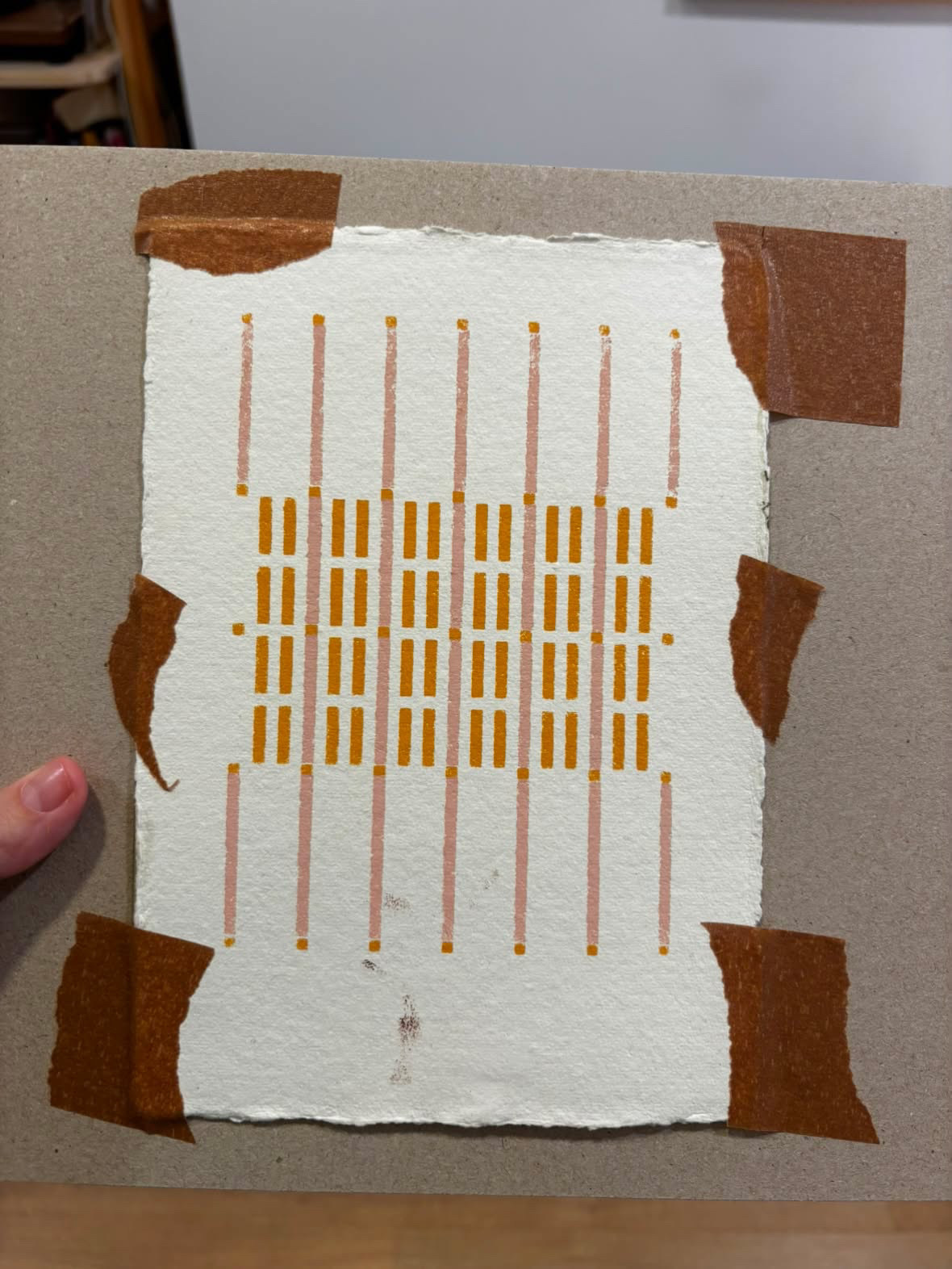 An invitation print with its first layers of color, taped for registration